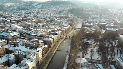 A drone shot over the Miljacka river in the Bosnian capital Sarajevo during a sunny sunrise. One of