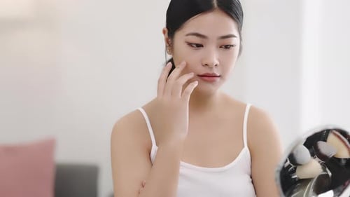 Slow motion shot Close up beauty young pan Asian woman looking at a mirror and applying cosmetics.