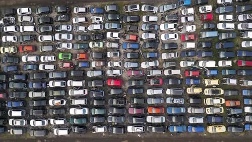 Luftaufnahme von oben nach unten eines verlassenen Autofriedhofs voller alter, beschädigter und unbenutzter Fahrzeuge