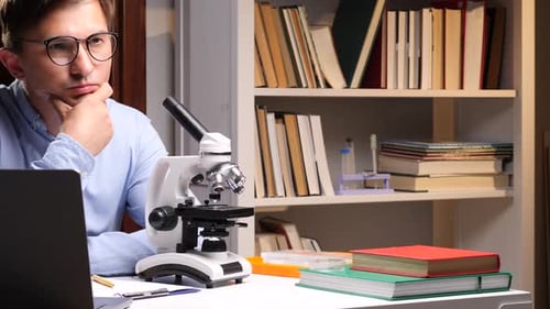 Thoughtful Young Adult Scientist with Microscope