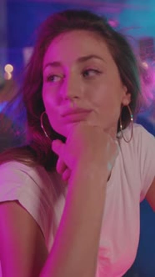 Une jeune femme illuminée par un éclairage coloré dans une atmosphère de fête animée