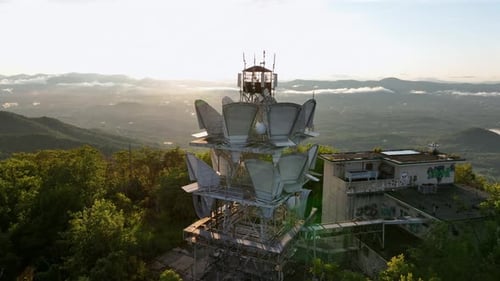 Aerial view of American radio tower on top of green mountains during sunrise. Graffiti on wall of