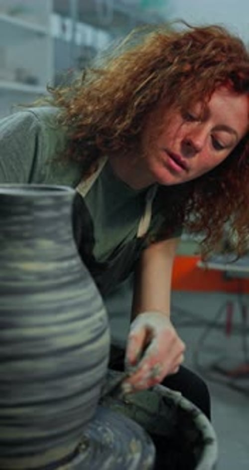Woman Shapes Clay on Pottery Wheel in Studio