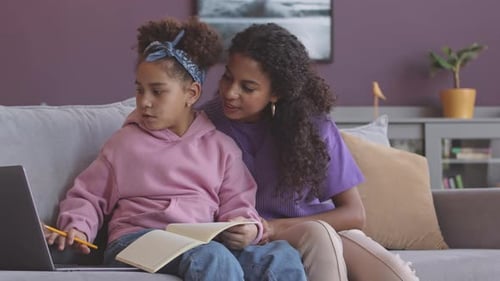 Girl doing Homework With Assistance From Adult Woman