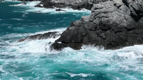 Aerial Footage of Turquoise Ocean Waters Washing Rugged Rocky Shoreline