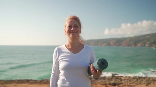Senior Woman Holding Yoga Mat Standing on Beach