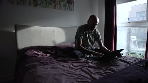 Man Working on Laptop Computer in Bedroom