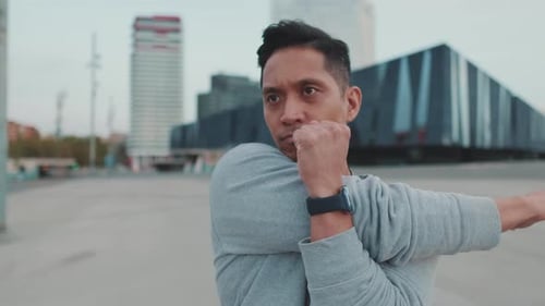 Junger Mann streckt vor dem Training seine Armmuskeln