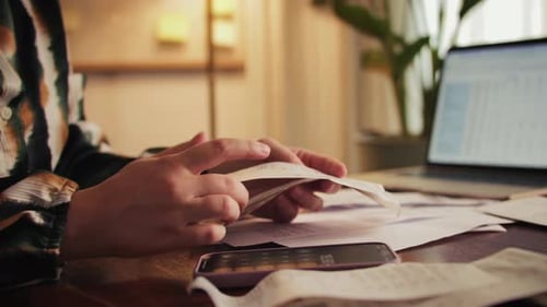Woman Sorts Receipts Using a Calculator to Track Expenses at Home Budget Planning or Tax Return From