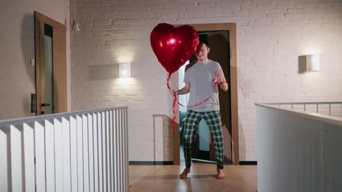 Man Holding Heart Balloon in Hallway