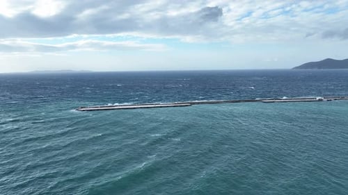 Aerial footage of a harbor pier during a storm with tall waves