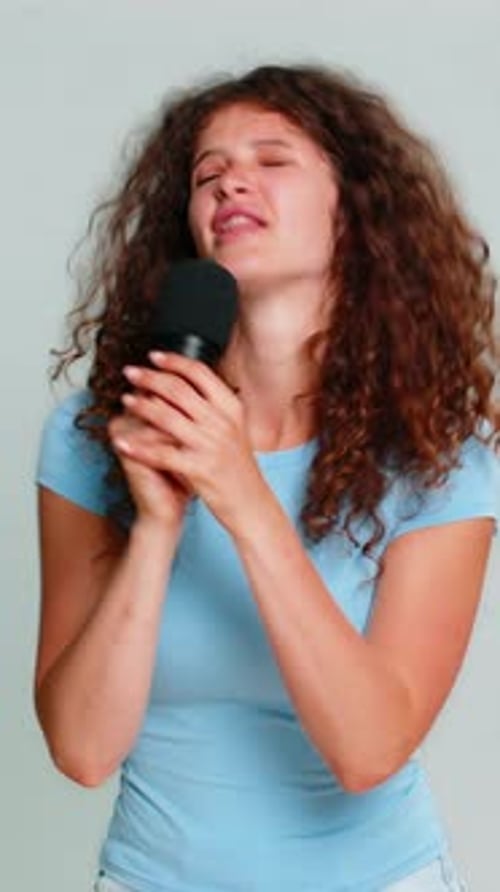 Woman Singing Passionately into Microphone in Studio
