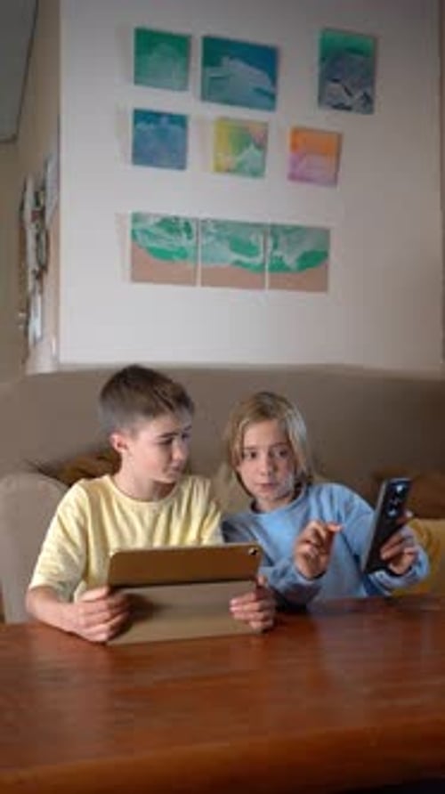 Children Using Tablet and Phone at Wooden Table