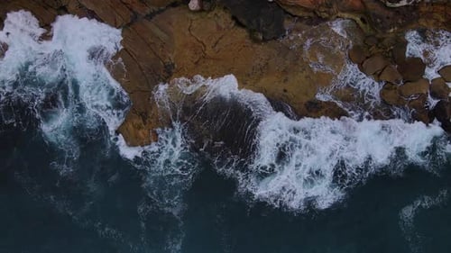 Above drone shot of rocks being lapped with waves . Ocean and sea stock videos