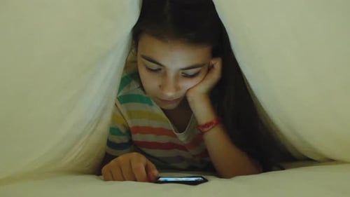 Girl Using Smartphone Under Blanket at Night