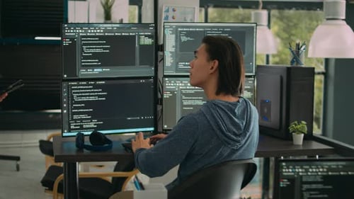 Man Coding at Multiple Monitors in Modern Office