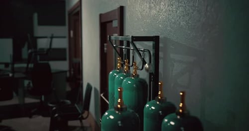 Green Gas Cylinders Lined Up in a Dimly Lit Industrial Workspace