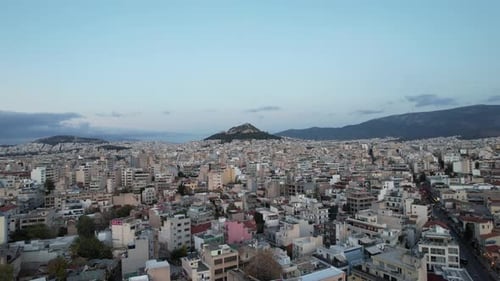 Aerial drone view over the cityscape towards Mount Lycabettus, dusk in Athens, Greece