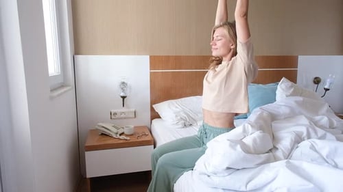 Woman Wakes and Stretches in Hotel Bed