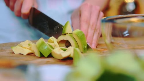 Cutting fresh avocado into pieces with knife