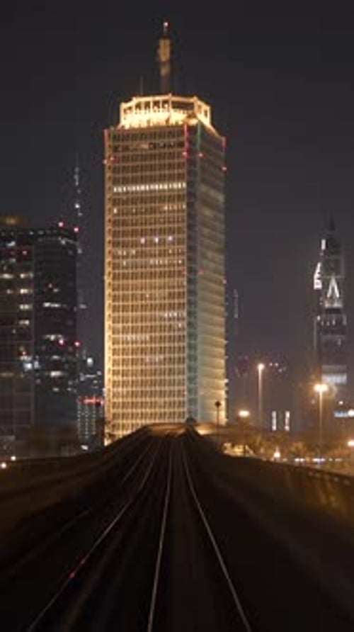 An Illuminated Skyscraper at Night with an Expansive Urban Skyline in the Background