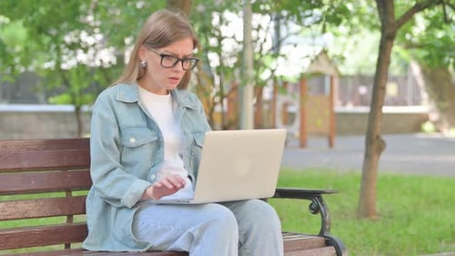 Perplexed Young Woman Using Laptop on Park Bench