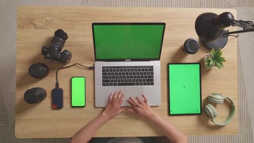Vue du dessus Vue en zoom arrière d'une femme monteuse vidéo utilisant un ordinateur portable, un smartphone et une tablette à écran vert