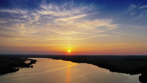 Atemberaubender orangefarbener Sonnenuntergang über dem Fluss. Magisches Luftbild der Abendsonne zwischen Wolken.