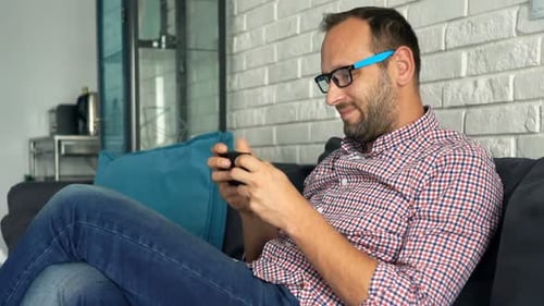 Man relaxing on couch using smartphone device