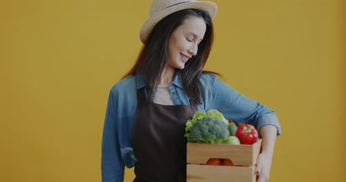 Smiling Woman Holding Crate of Fresh Organic Vegetables