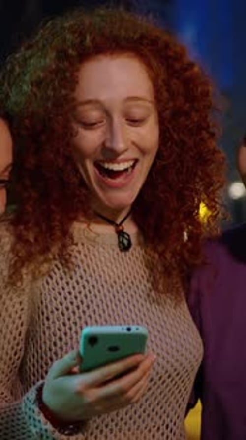 Two Women Looking at Smartphone at Night