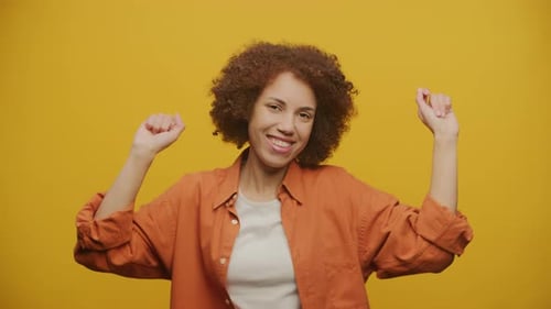 Happy Woman Dancing in Front of Yellow Background