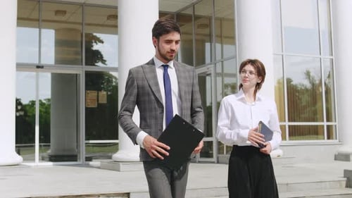 Professionals Discussing Plans Outside a Modern Building on a Sunny Day During a Business Meeting