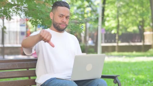 Thumbs Down by Middle Aged Man Using Laptop while Sitting Outdoor on Bench