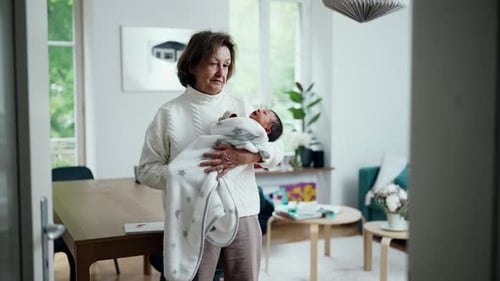 Senior Woman Holds Newborn Baby Indoors