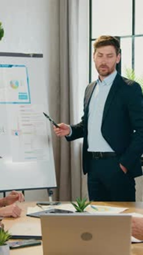Man Presenting Financial Data on Whiteboard in Office