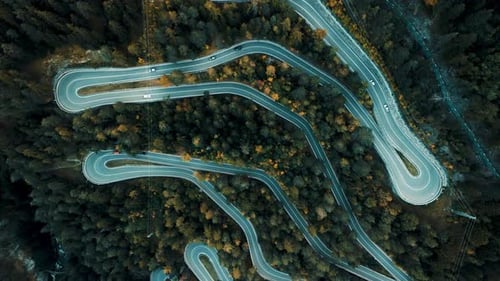 Aerial 4k Drone Footage of a winding mountain road through a pine forest, Alps, Italy