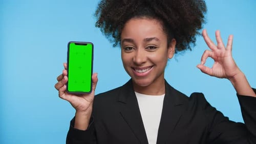 Woman Holding Smartphone with Green Screen on Blue