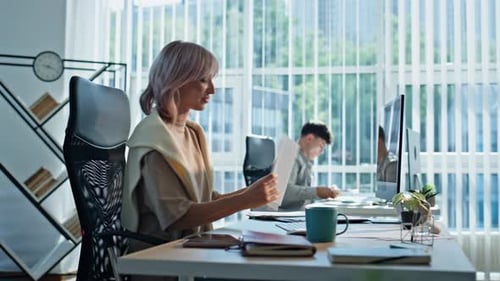 Femme positive regardant des documents dans un espace de coworking Responsable travaillant au bureau