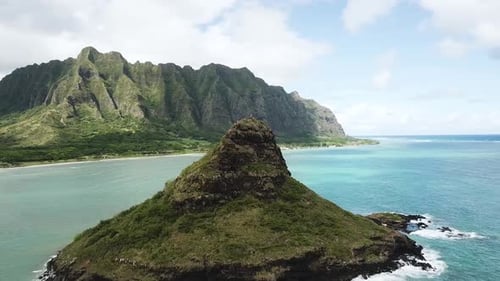 Tiro de drone se aproximando do chapéu do homem chinês (Mokoli'i) com a cordilheira de Kualoa ao fundo.