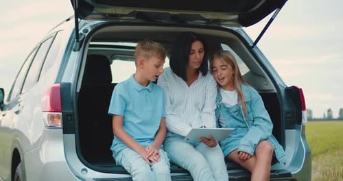Mother and Children Using Tablet on Road Trip