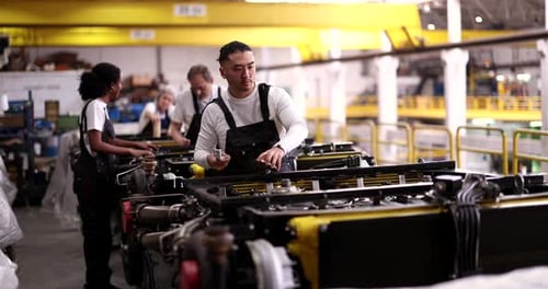 Groupe multiethnique d'ouvriers d'usine qualifiés en uniforme collaborant sur une chaîne de production, assemblage