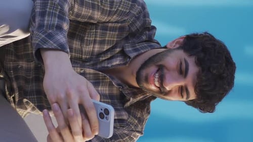 Vertical Video of Handsome and happy young man texting on his smartphone.