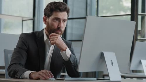Serious Man Working at Computer in Modern Office