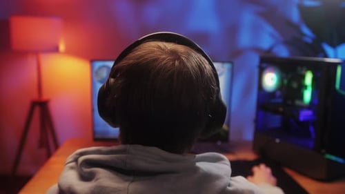 Young Man Has a Video Game Stream or Podcast in Neon Room Male Gamer Playing Online Video Games on