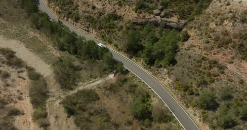 Camper Van Driving Along Winding Road Through Northern Spanish Countryside Captured by Drone