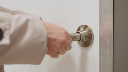 Female Hand Unlocking Door With Key To Enter Room