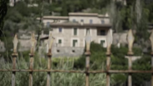 Statisches Video mit Rack-Fokus zwischen einem Eisenzaun und einem rustikalen Steinhaus