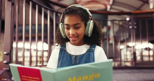 Learning, child and reading book with headphones, library and happy with fiction, knowledge or info