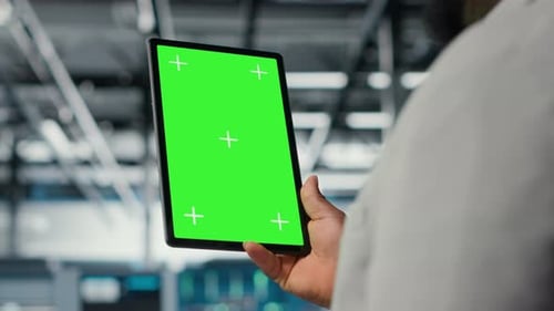 Technician Upgrading Equipment in Data Center Using Green Screen Tablet